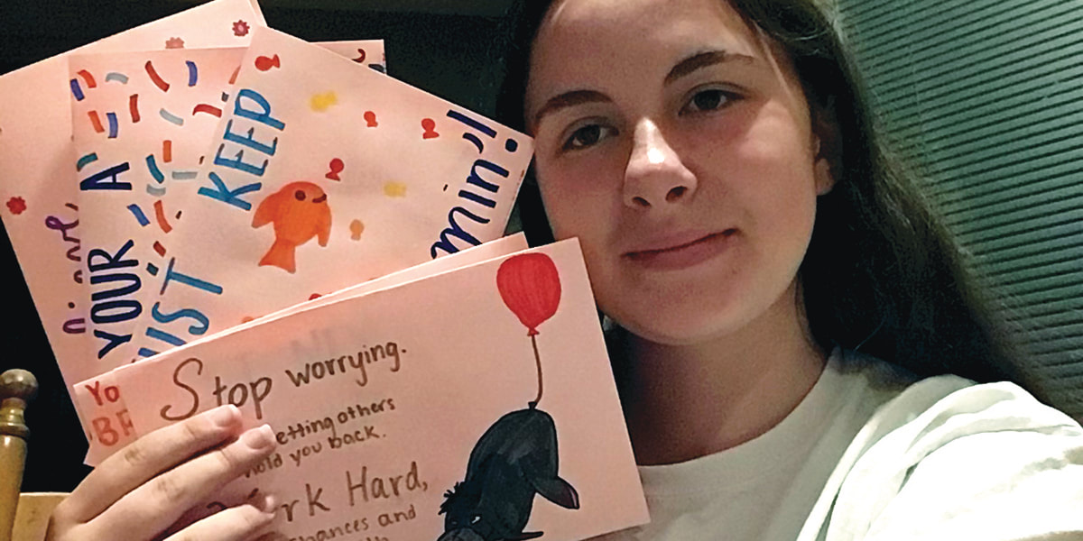 Photo of a teen holding 4 cards they made as a service project through the library's online volunteer program