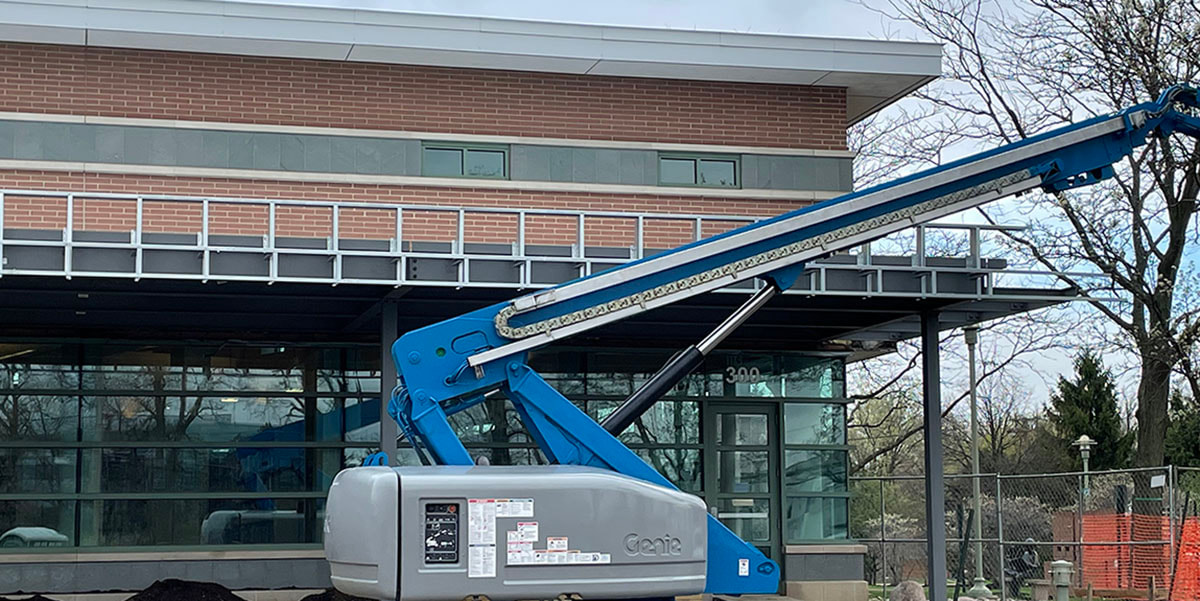 April 9 photo showing a construction crane and new steel soffit for the covered walkway at the library.