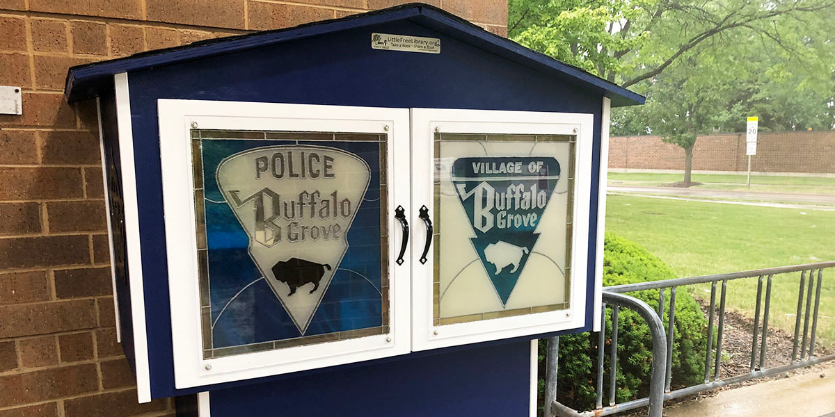Photo of a Little Free Library box featuring the crests of the police and Village Buffalo Grove