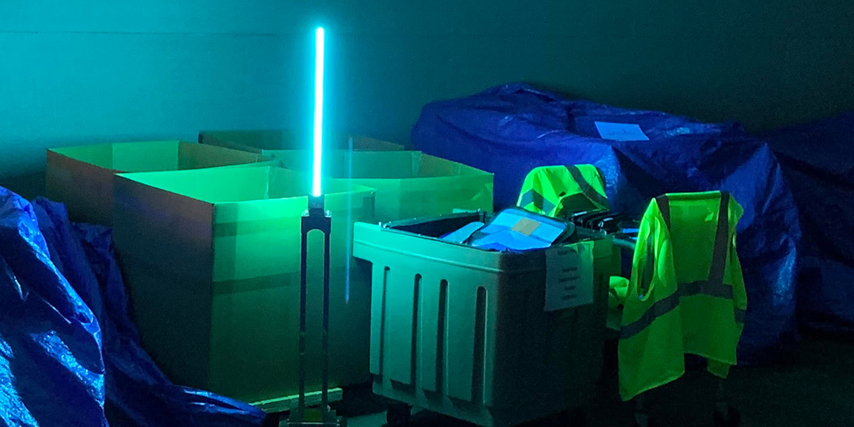 Ultraviolet light shines an eerie glow on bins of returned books and safety vests